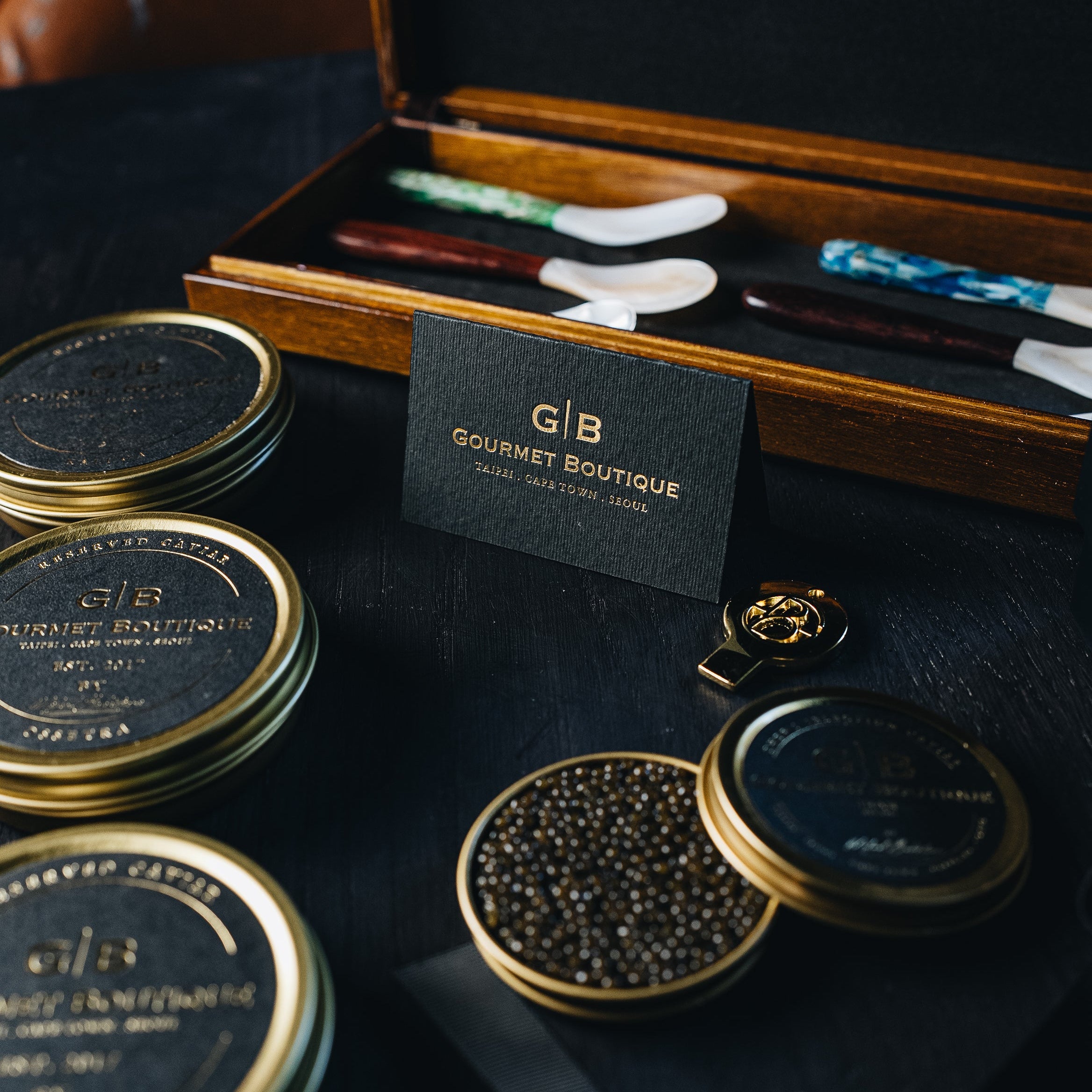 Caviar tins with accessories on a dark surface